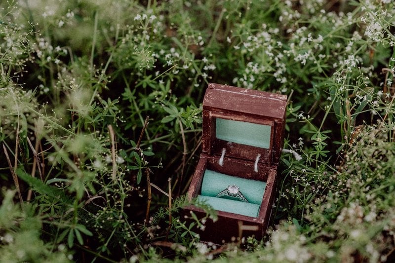 diamantový zásnubný prsteň na saténovej látke v drevenej krabičke na tráve