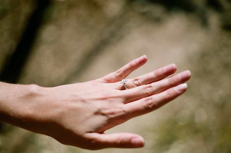 detailný záber na ženskú ľavú ruku s diamantovým prsteňom na prstenníku