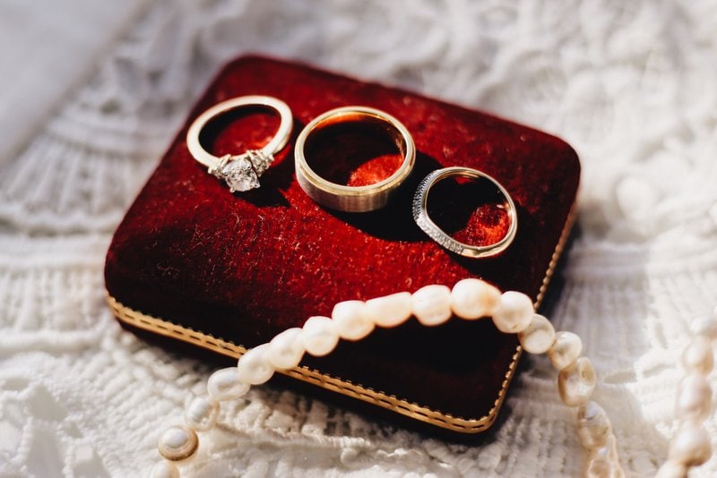 tri prstene a jeden náramok uložené na červenom vankúšiku