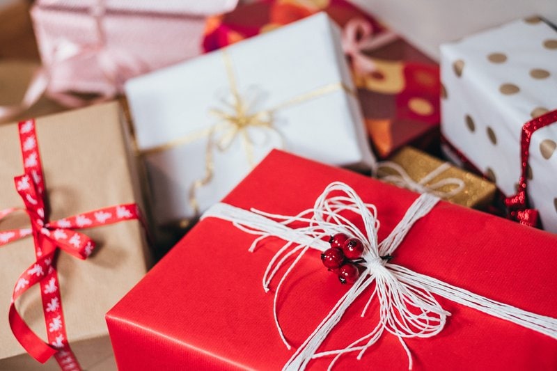vianočné darčeky zabalené v červenom, zlatom a bielom obale previazané šmúrkami