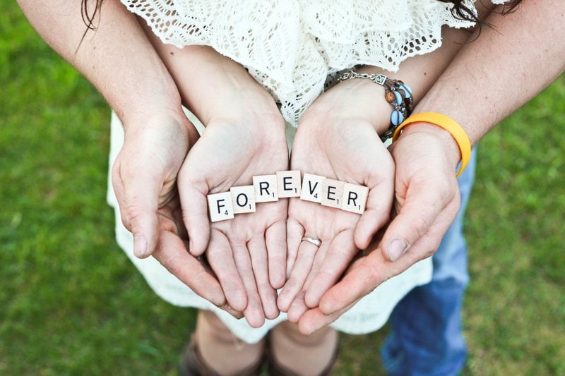 slovo forever vytvorené z kociek scrabble v spojených rukách ženy a muža