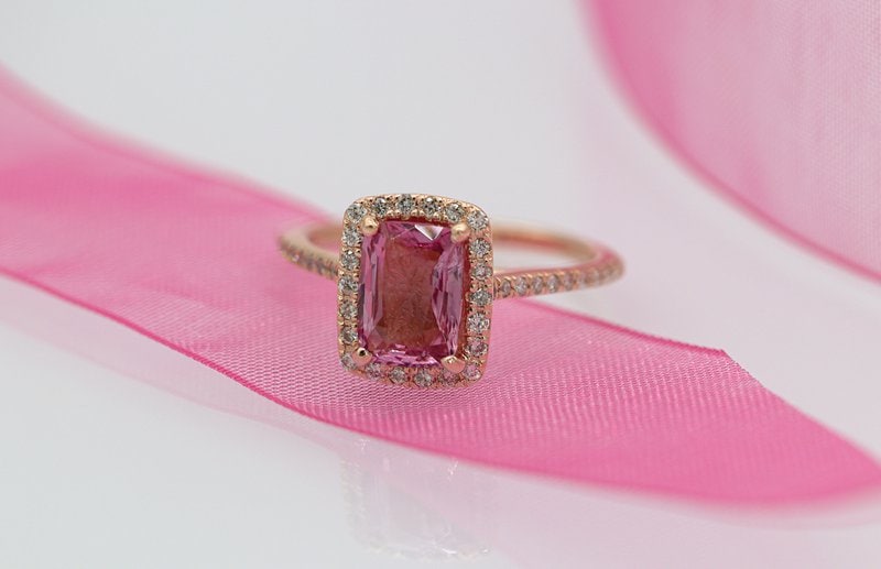 zásnubný prsteň z ružového zlata s ružovým diamantom položený na ružovej stuhe