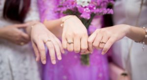 tri ženské ruky ukazujúce diamantové zásnubné prstene
