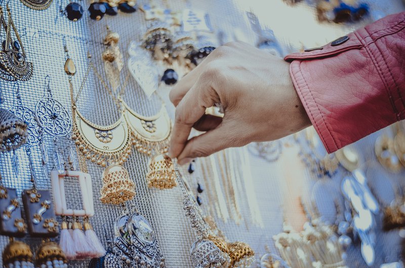 ženská ruka si vyberá náušnice zavesené na priehľadnej sieťke na trhu